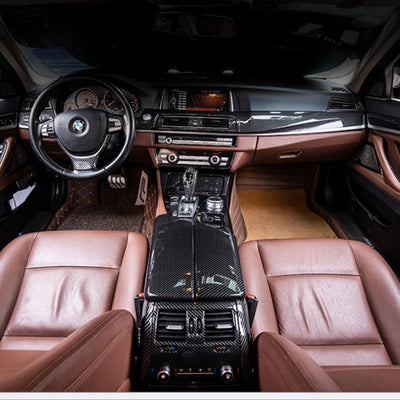Vedere superioară a consolei centrale cu protecția de cotieră din fibră de carbon montată pe BMW F10. Interior maro, design ergonomic și sportiv.