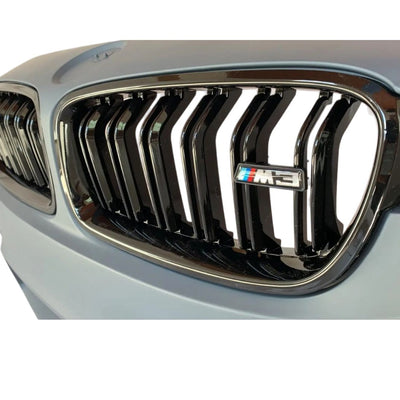 Grilă centrală dublu-rinichi BMW cu finisaj lucios Piano Black și emblemă M3 integrată. Vedere de aproape pe bara față M3 Style compatibilă cu Seria 3 F30/F31